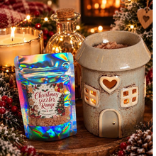 Load image into Gallery viewer, A festive display of handmade Christmas luxury scented sizzlers granules sitting next to a gingerbread wax warmer on a traditional Christmas background scene